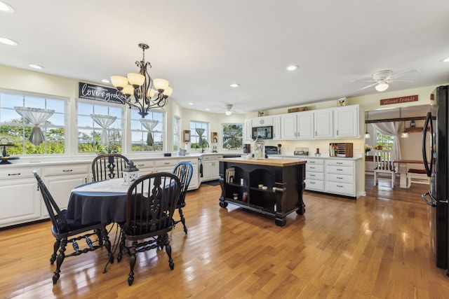 dining area featuring ceiling fan with notable chandelier, a healthy amount of sunlight, sink, and light hardwood / wood-style floors