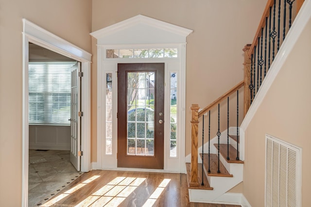 foyer featuring stairway, baseboards, wood finished floors, and visible vents
