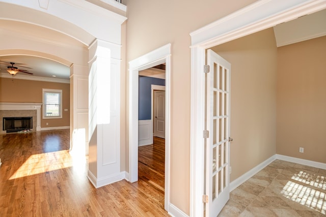 hall featuring baseboards, wood finished floors, arched walkways, and ornamental molding