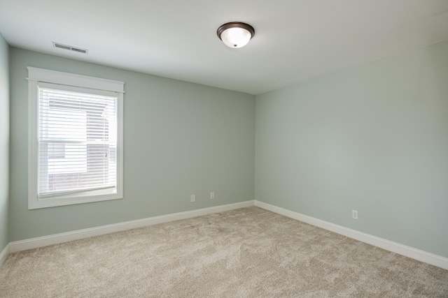 carpeted spare room featuring baseboards and visible vents