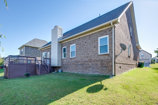 rear view of property featuring a lawn, a chimney, brick siding, and a deck