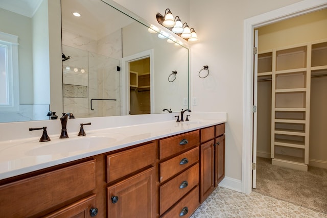 bathroom with a spacious closet, a sink, a marble finish shower, and double vanity