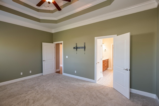 unfurnished bedroom featuring a raised ceiling, light carpet, baseboards, and ornamental molding