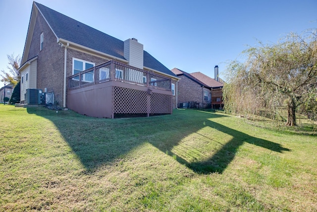 rear view of property featuring a lawn, a chimney, brick siding, and a deck