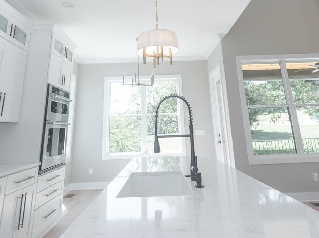 kitchen featuring white cabinets, sink, a notable chandelier, crown molding, and hanging light fixtures