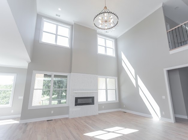 unfurnished living room featuring plenty of natural light, a towering ceiling, and light hardwood / wood-style floors