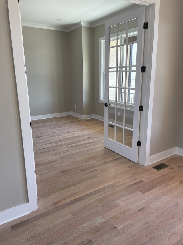 empty room featuring crown molding and light wood-type flooring