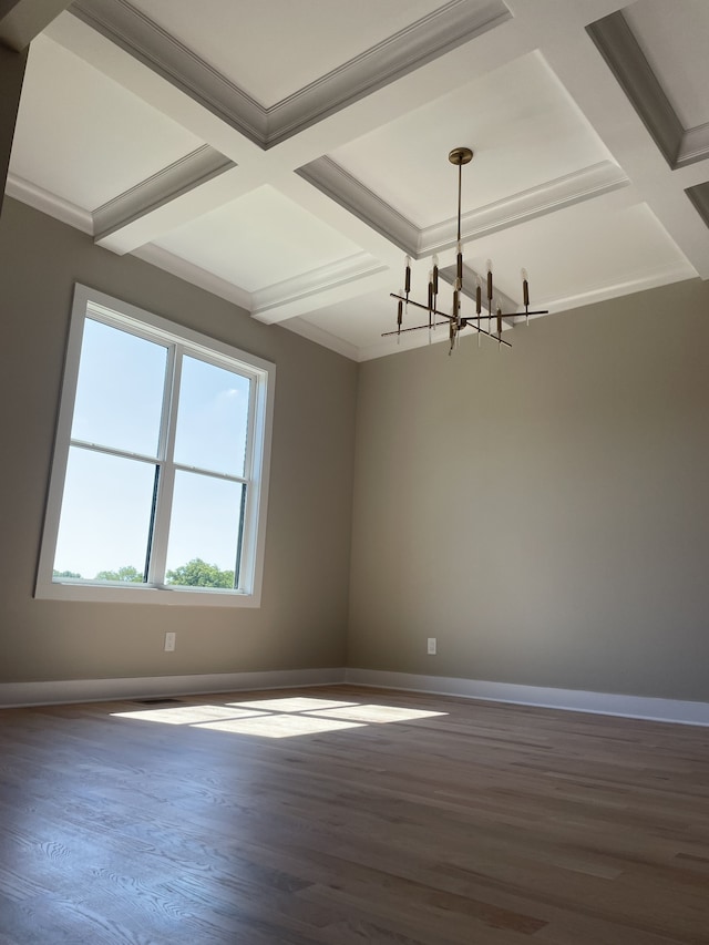 unfurnished room featuring coffered ceiling, an inviting chandelier, dark hardwood / wood-style floors, and ornamental molding