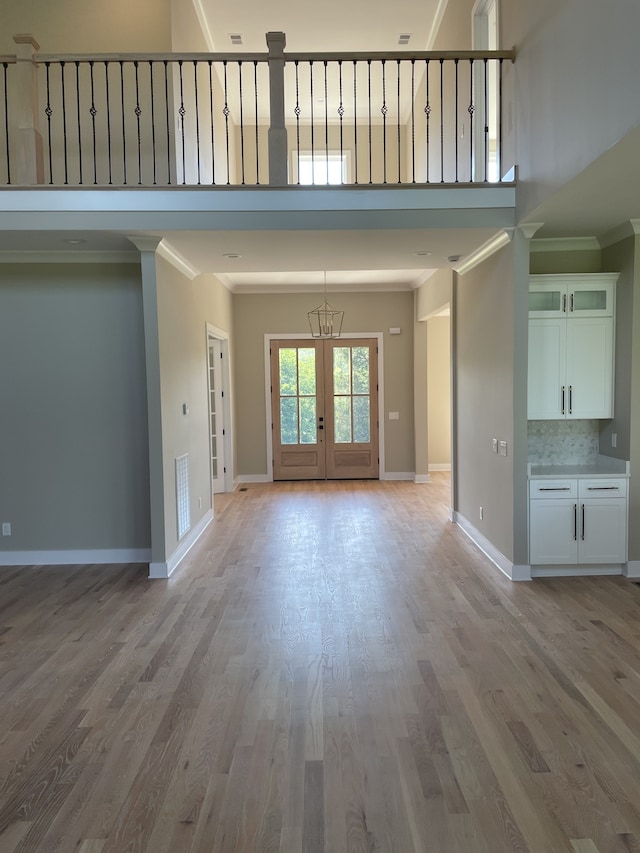 interior space featuring ornamental molding, light wood-type flooring, and french doors