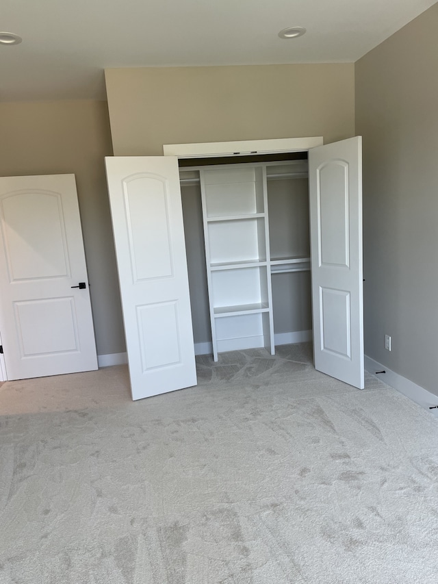 unfurnished bedroom with a closet and light carpet