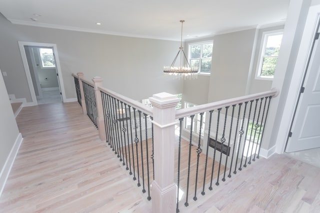 staircase with wood-type flooring, ornamental molding, and a notable chandelier