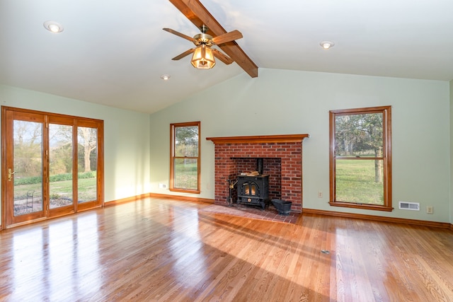 unfurnished living room with ceiling fan, vaulted ceiling with beams, light wood-type flooring, and a wood stove