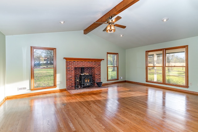 unfurnished living room with ceiling fan, lofted ceiling with beams, light hardwood / wood-style flooring, and a wood stove