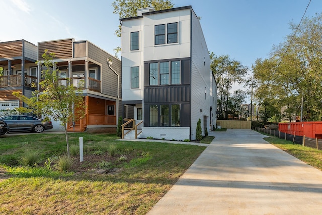 contemporary house featuring a balcony and a front lawn