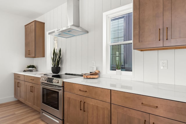 kitchen with wall chimney exhaust hood, stainless steel electric range oven, and light hardwood / wood-style flooring