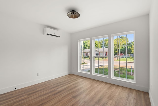 empty room featuring a wall mounted air conditioner and light hardwood / wood-style flooring