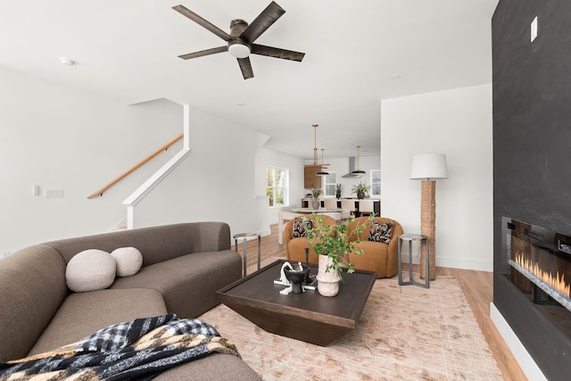 living room featuring ceiling fan, light wood-type flooring, and a fireplace