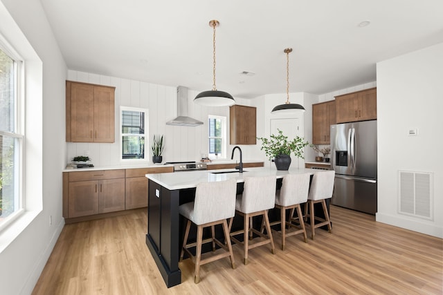 kitchen with stainless steel appliances, wall chimney exhaust hood, and a wealth of natural light