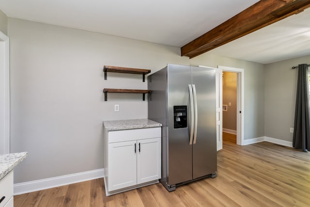 kitchen featuring beamed ceiling, light hardwood / wood-style flooring, light stone counters, white cabinets, and stainless steel refrigerator with ice dispenser