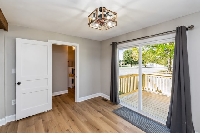 spare room with water heater and light hardwood / wood-style floors