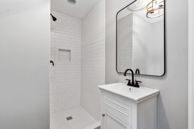 bathroom featuring tiled shower and vanity