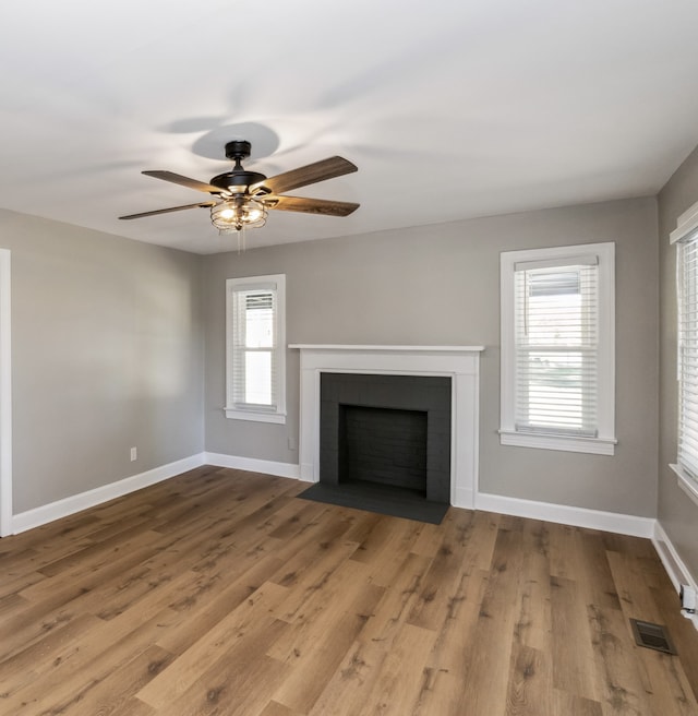 unfurnished living room featuring light wood-type flooring, a healthy amount of sunlight, and ceiling fan