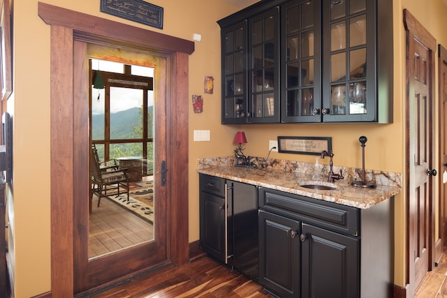 bar with a mountain view, light stone countertops, sink, and dark hardwood / wood-style flooring