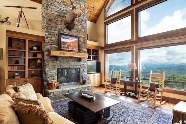 living room with a stone fireplace, hardwood / wood-style floors, high vaulted ceiling, and a wealth of natural light