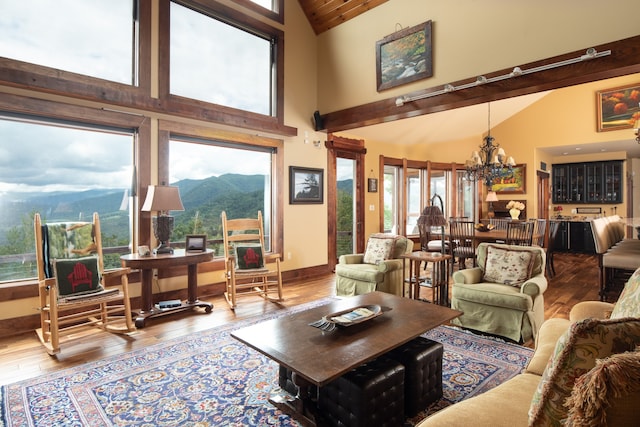 living room with a mountain view, a notable chandelier, wood-type flooring, and plenty of natural light