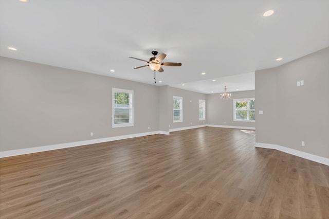 spare room featuring ceiling fan with notable chandelier and light hardwood / wood-style floors