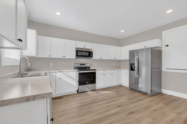 kitchen featuring light hardwood / wood-style floors, sink, stainless steel appliances, and white cabinets