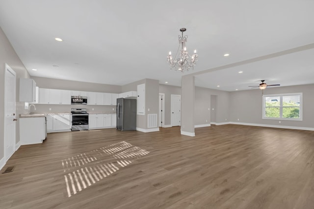 unfurnished living room with ceiling fan with notable chandelier, light wood-type flooring, and sink