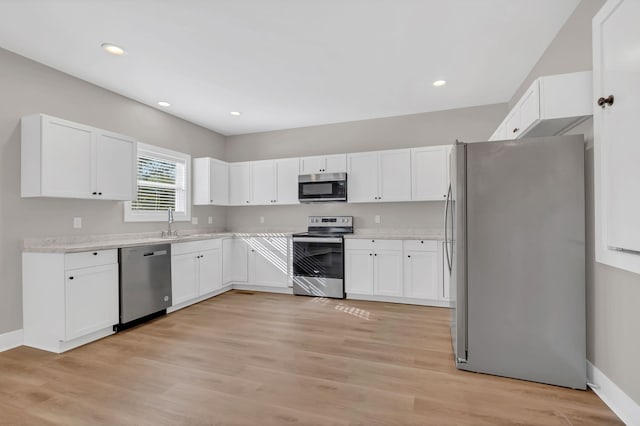 kitchen with appliances with stainless steel finishes, light wood-type flooring, and white cabinetry