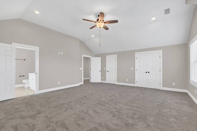 unfurnished bedroom featuring ceiling fan, carpet floors, ensuite bath, and vaulted ceiling