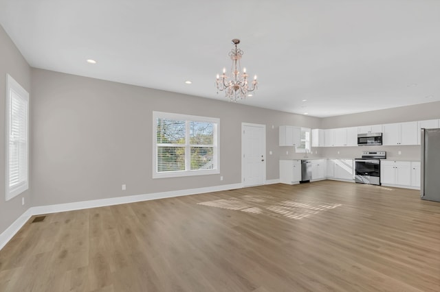 unfurnished living room with a notable chandelier and light hardwood / wood-style floors