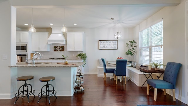 kitchen featuring white cabinetry, dark hardwood / wood-style flooring, pendant lighting, and custom exhaust hood