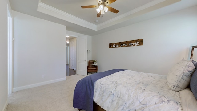 carpeted bedroom with ceiling fan, a raised ceiling, and crown molding