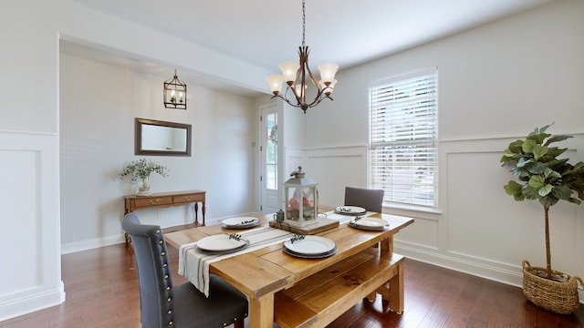 dining area with dark wood-type flooring and an inviting chandelier