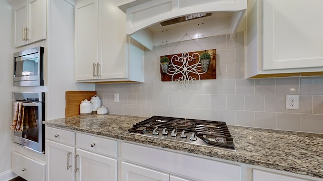 kitchen featuring white cabinetry, light stone counters, stainless steel appliances, and decorative backsplash