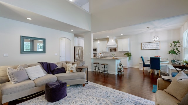 living room with a notable chandelier, dark hardwood / wood-style floors, sink, and a high ceiling