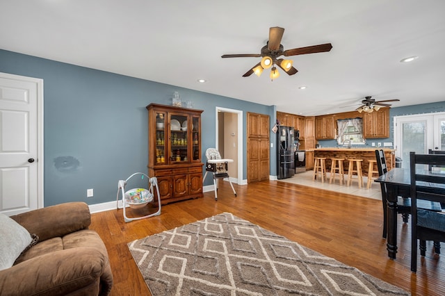 living room featuring light hardwood / wood-style floors, sink, and ceiling fan