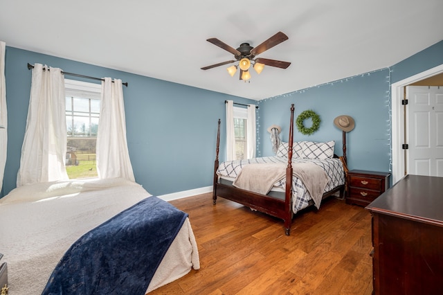 bedroom featuring ceiling fan, hardwood / wood-style floors, and multiple windows