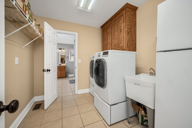 washroom featuring washing machine and clothes dryer, sink, light tile patterned floors, and cabinets