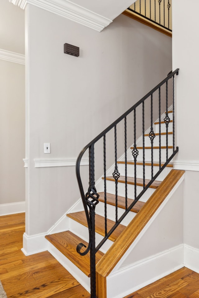 stairway with hardwood / wood-style flooring and crown molding