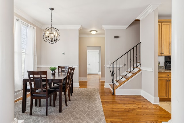 dining area featuring light hardwood / wood-style flooring, ornamental molding, and a notable chandelier