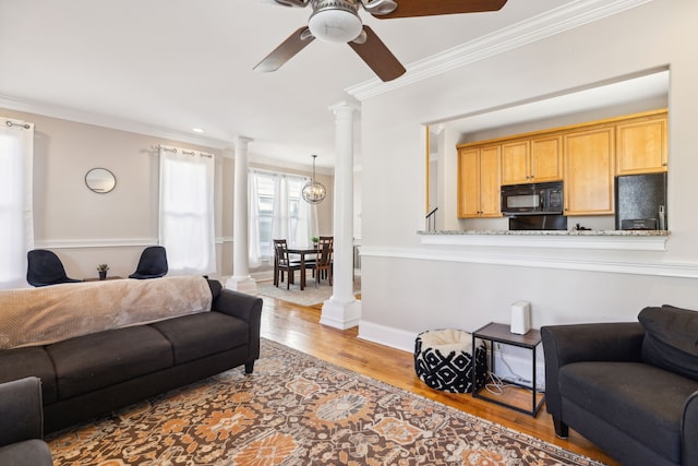 living room with ceiling fan, light wood-type flooring, crown molding, and decorative columns