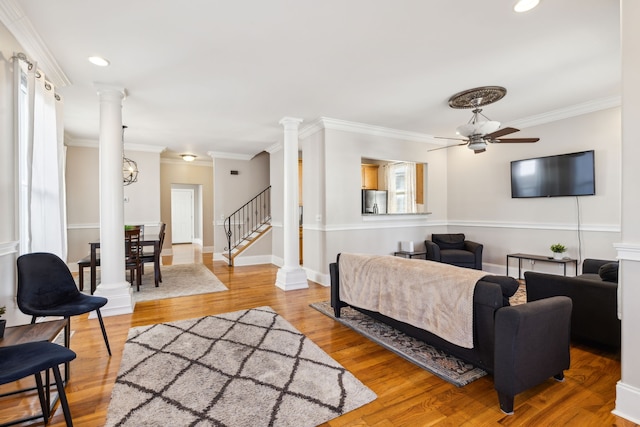 living room featuring ceiling fan with notable chandelier, hardwood / wood-style flooring, and crown molding