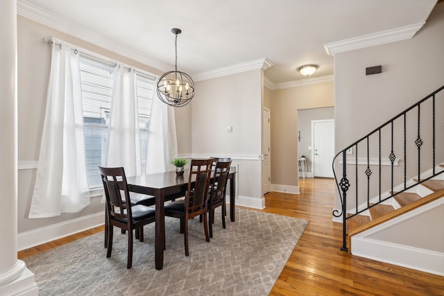 dining room with wood-type flooring, an inviting chandelier, and crown molding