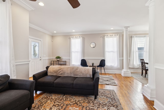 living room featuring plenty of natural light, light wood-type flooring, ornamental molding, and ornate columns