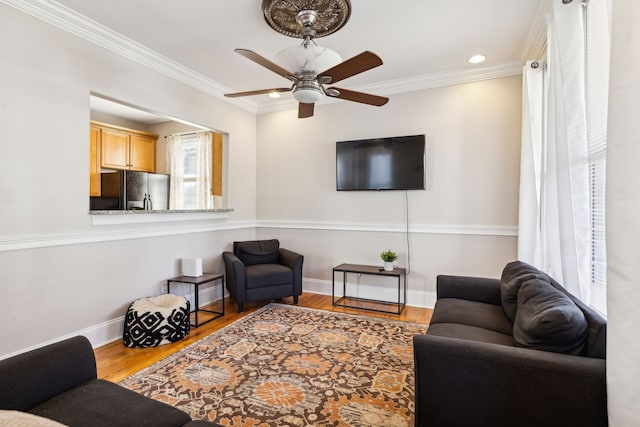 living room featuring wood-type flooring, ceiling fan, and crown molding